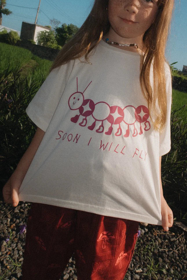 child wearing Soon I will Fly Tee by Sauce Mini with burgundy caterpillar graphic on the front