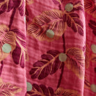 Close-up view of pink baby wrap fabric showing tropical leaf print and woven cotton texture