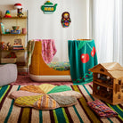 Pink tropical print baby wrap displayed in colorful children's playroom with toys and dollhouse
