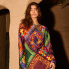 Close-up upper-body shot of a woman wearing a vibrant multicolour scarf-print long-sleeve maxi dress