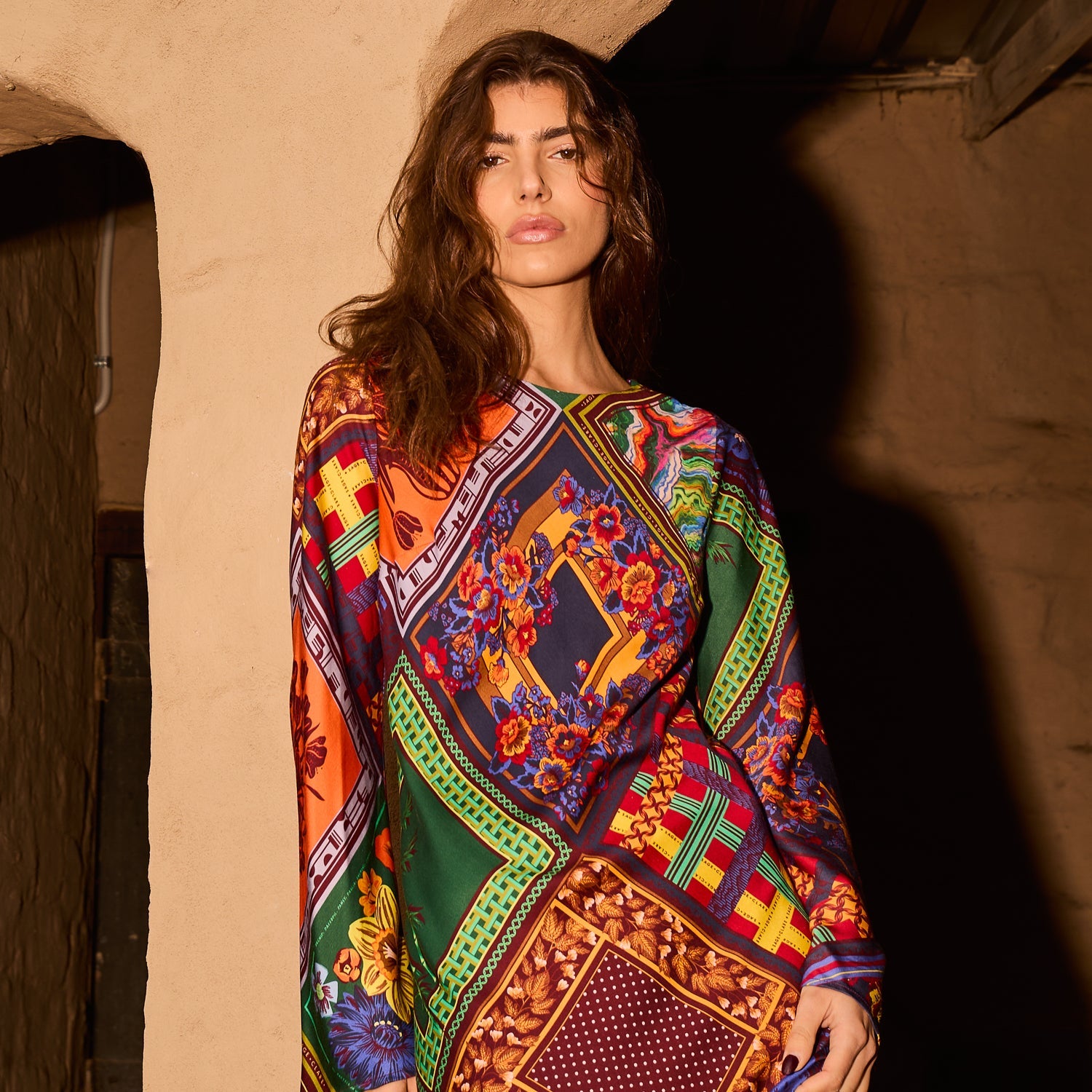 Close-up upper-body shot of a woman wearing a vibrant multicolour scarf-print long-sleeve maxi dress