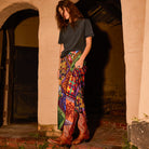 Front view of a multicolour patchwork-print satin maxi slip skirt styled with a grey tee and brown cowboy boots