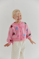 Front view of pink star cardigan showing button closure and colorful star motifs