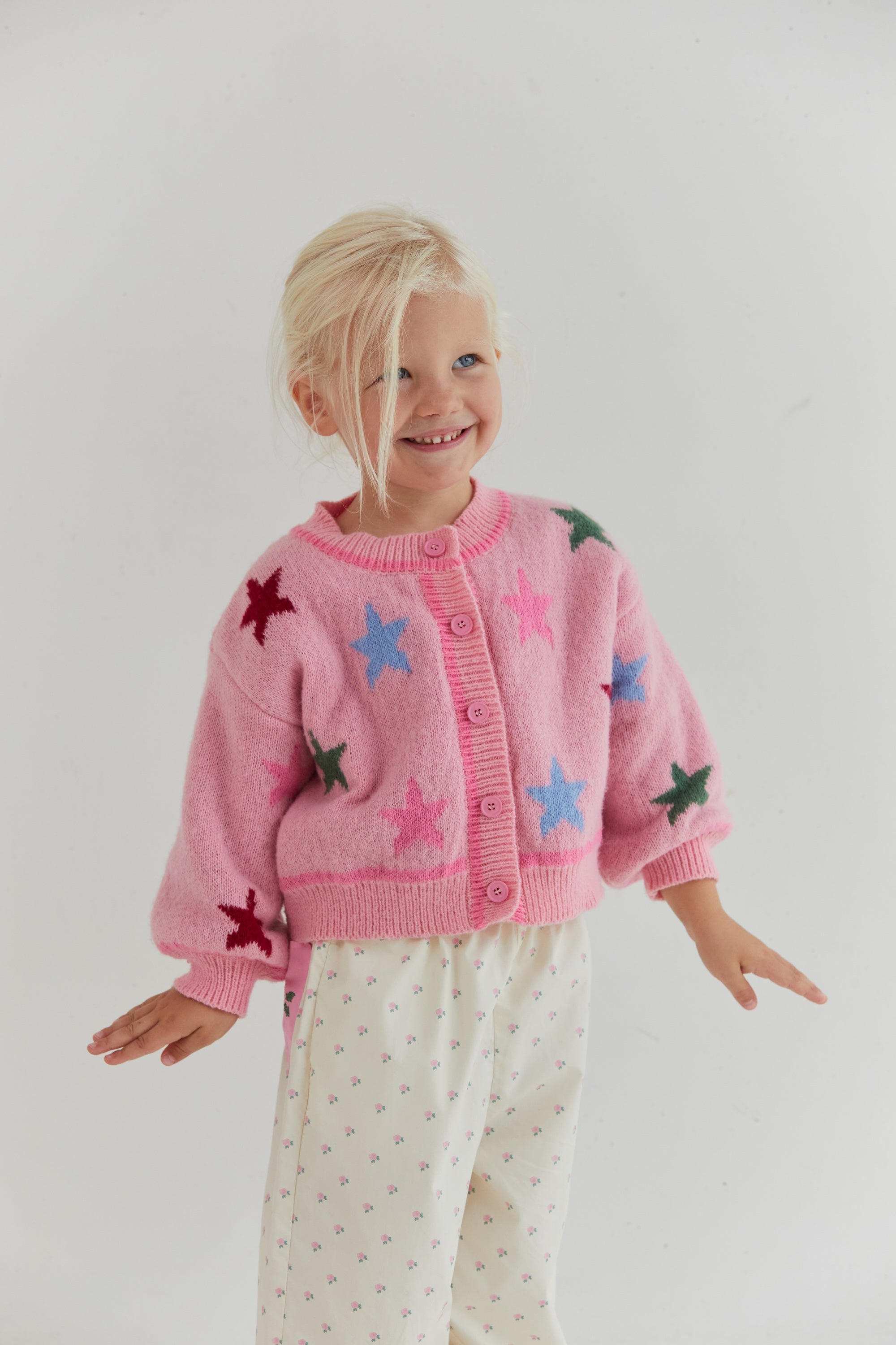 Front view of pink star cardigan showing button closure and colorful star motifs
