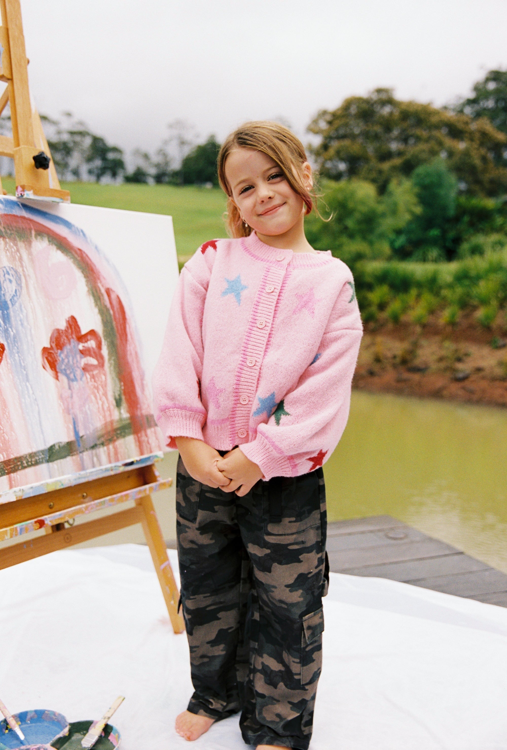 Child wearing pink star cardigan with button front and multicolored star design