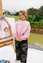 Child wearing pink star cardigan with button front and multicolored star design