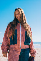 Front close-up of two tone pink and blue corduroy bomber jacket showing zip front teal collar and chest pockets at beach