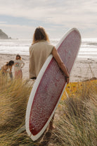 Back view of the cream surf coach front zip vest in size M worn by a woman carrying a longboard at the beach