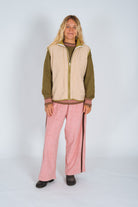 Full-length front view of the cream front zip vest in size M with olive trim worn open over a knit sweater