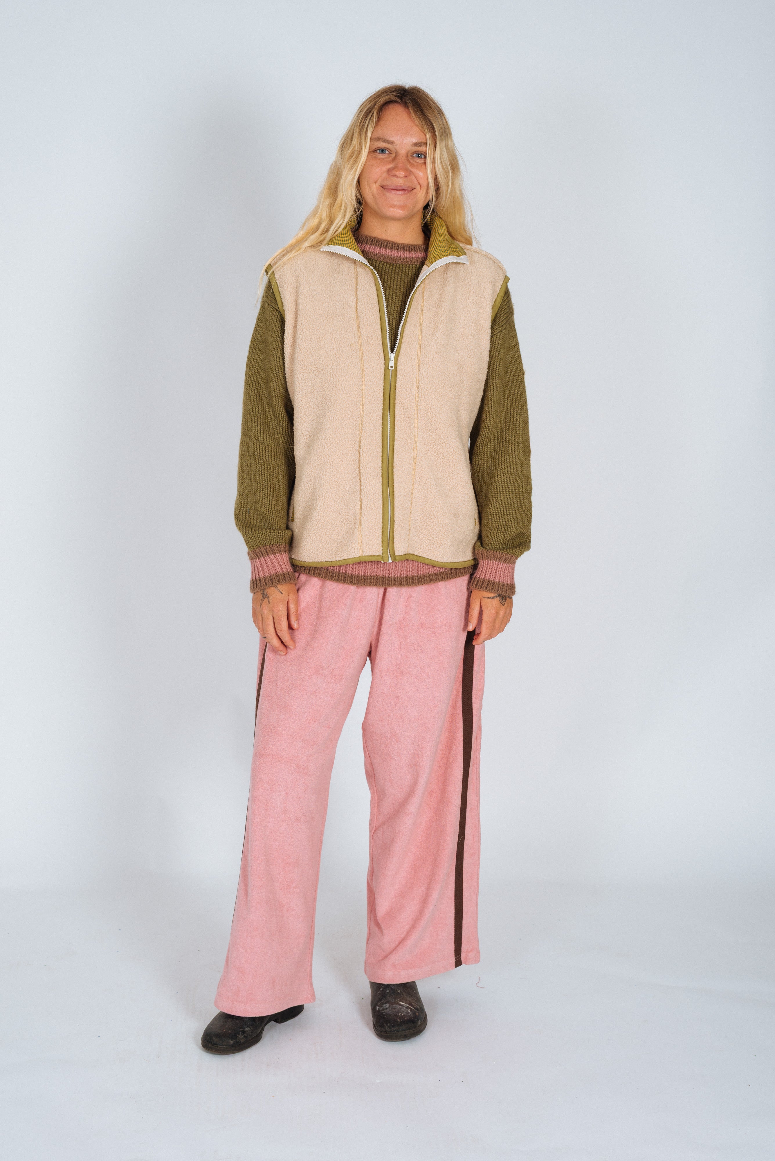 Full-length front view of the cream front zip vest in size M with olive trim worn open over a knit sweater