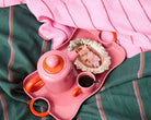 Pink espresso teapot and mug with orange handles on decorative tray with Turkish delight