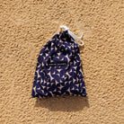 Navy patterned drawstring bag with 'Swim Shady' label on a sandy background