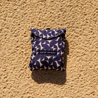 Folded fabric pouch with 'Swim Shady' branding on a beige textured surface