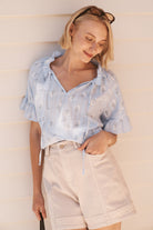 Close-up front view of cream high-waist denim shorts with front pockets and contrast stitching