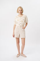 Full-length front view of cream high-waist denim shorts with contrast stitching and front patch pockets