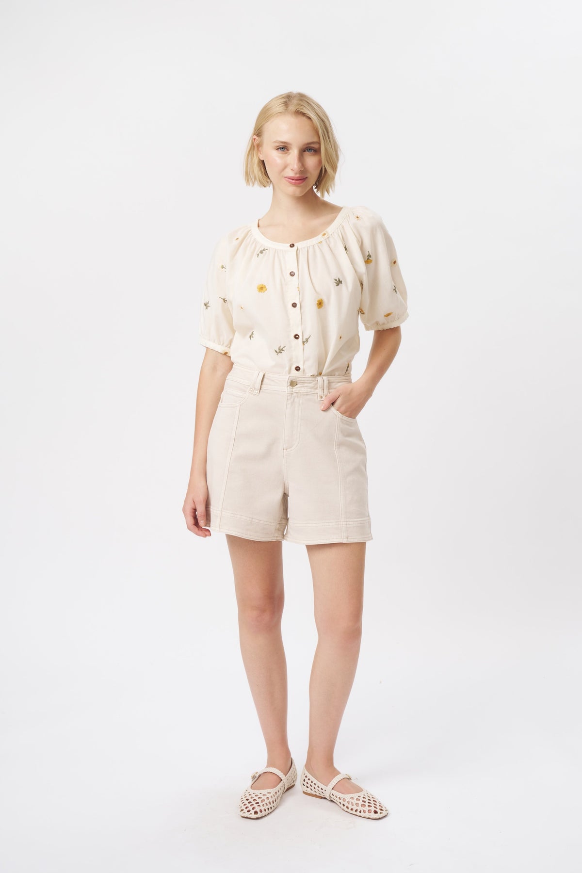 Full-length front view of cream high-waist denim shorts with contrast stitching and front patch pockets