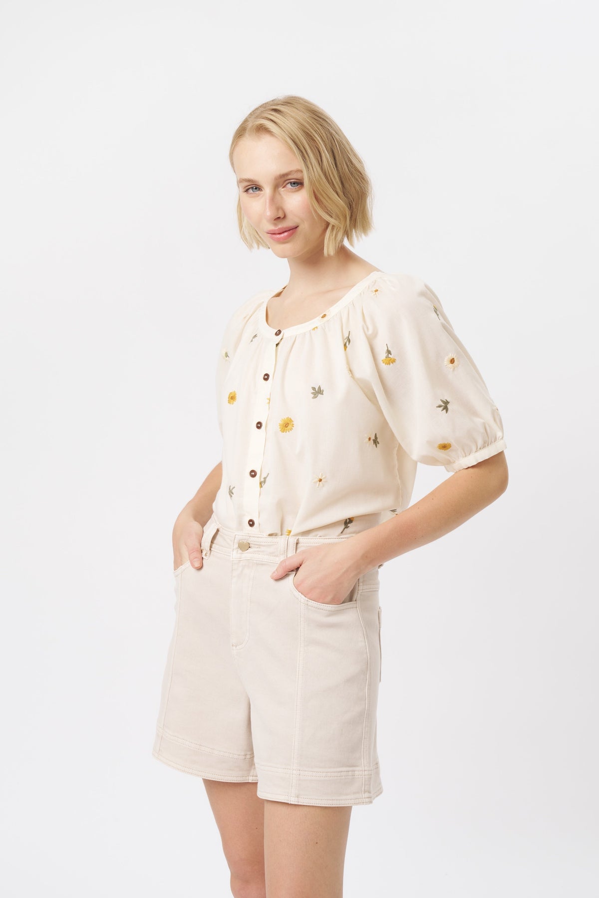 Side view of cream high-waist denim shorts with visible front pocket and contrast topstitching