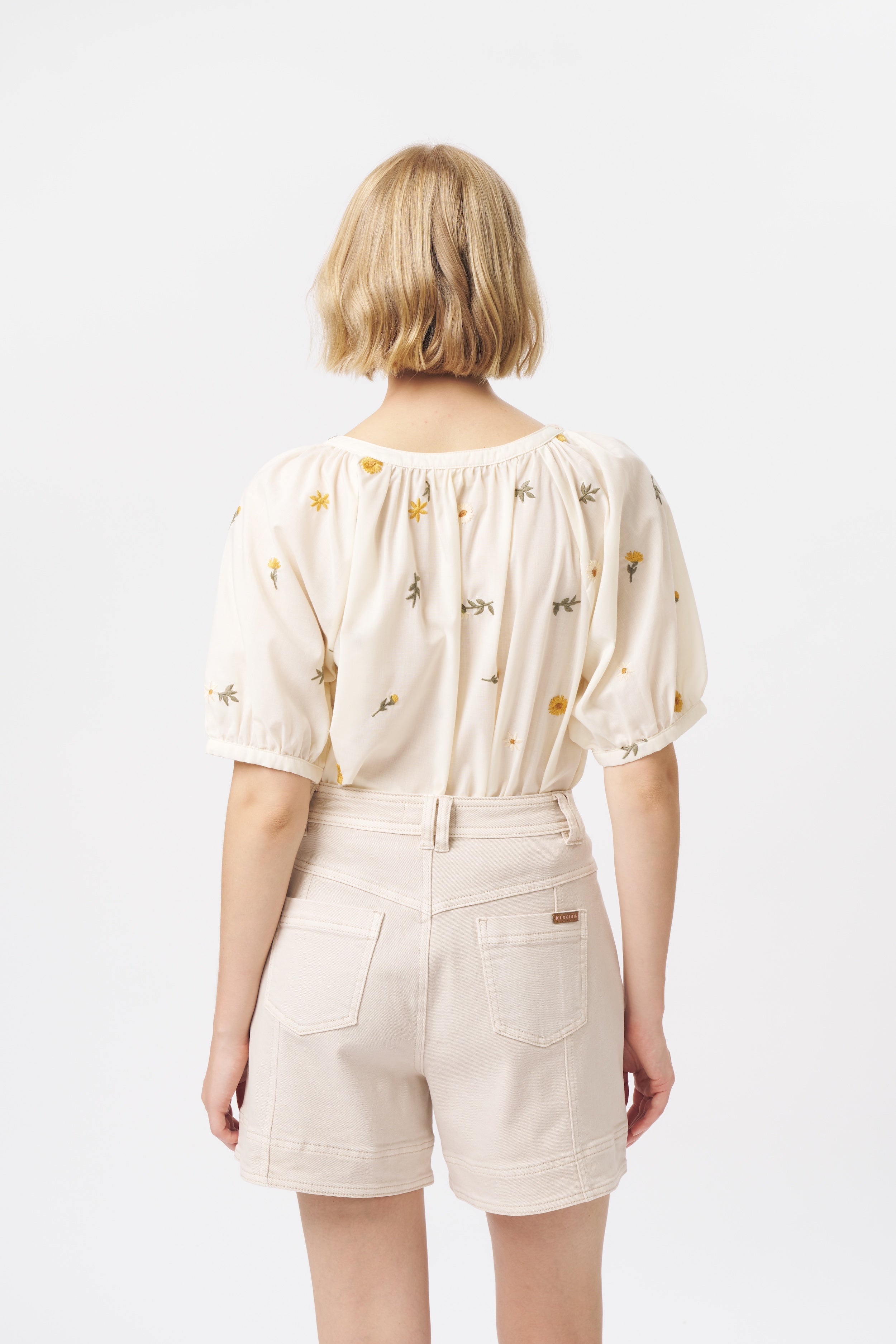 Back view of cream high-waist denim shorts with back patch pockets and contrast topstitching