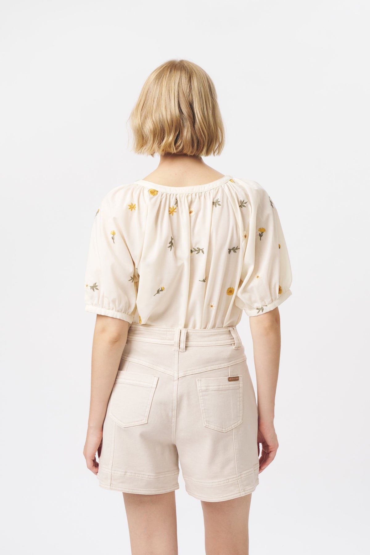 Back view of cream high-waist denim shorts with back patch pockets and contrast topstitching
