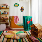 Green knit Tea Baby Blanket with cherry design draped over chair in bright children's bedroom