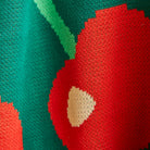 Close-up of knit fabric texture showing red cherry with tan center on Tea Baby Blanket