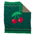 Flat lay of Tea Baby Blanket showing full cherry design with brown striped backing