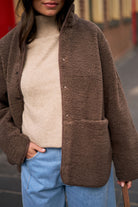 Close-up of chocolate brown teddy jacket showing snap button details and fluffy sherpa fleece texture
