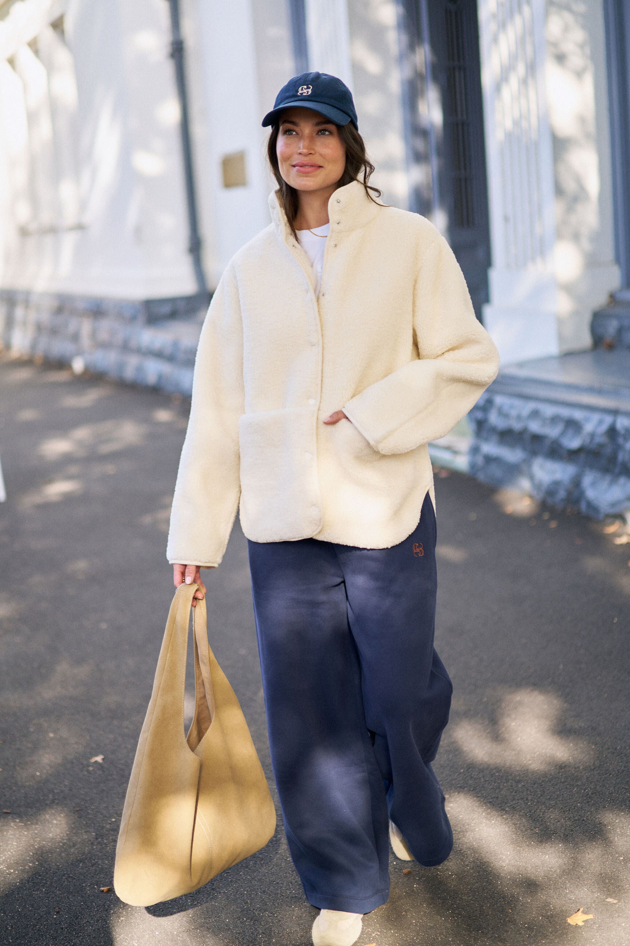 Woman wearing zipped marshmallow teddy jacket with baseball cap in casual street style