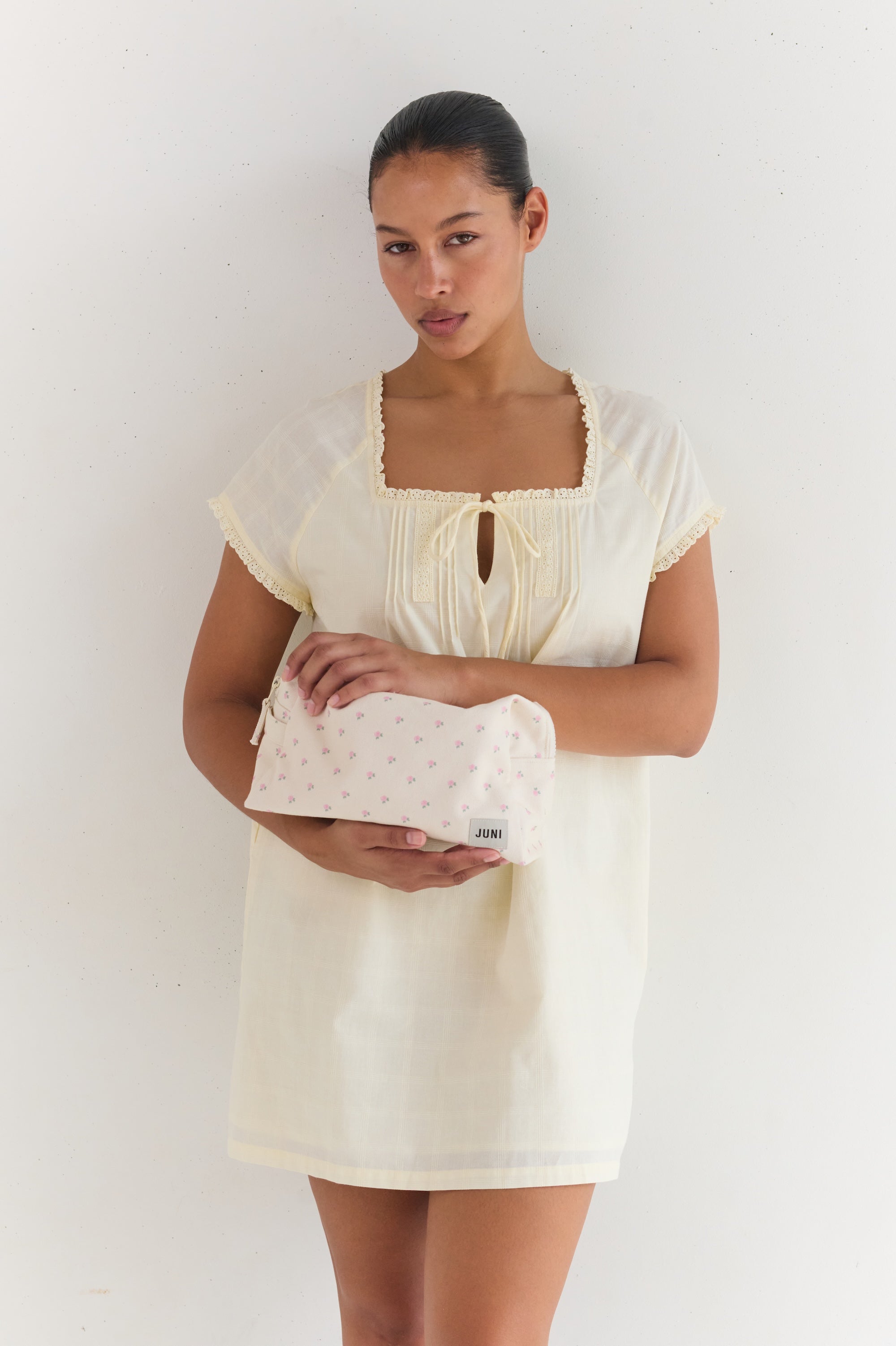 Front view of woman holding cream cotton Essentials Pouch with small pink roses pattern