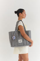 Side view of woman carrying Vichy gingham Everything Bag with quilted texture and rope handles