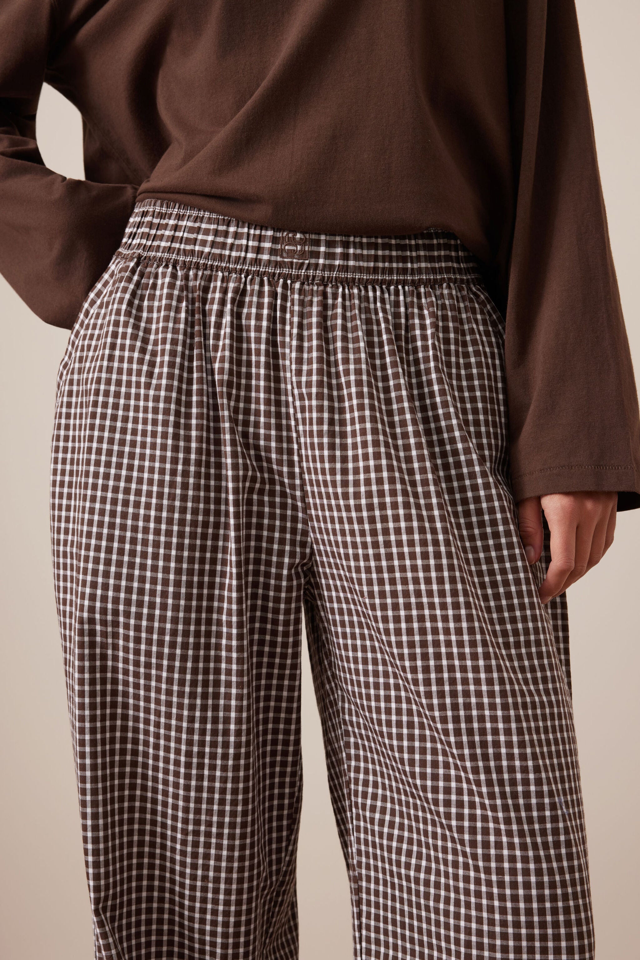 Close-up detail of chocolate check lounge pants showing elastic waistband and gingham fabric texture