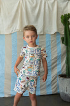 boy wearing The adventure-inspired tiled print t-shirt features crocodiles, snakes, boxing gloves, palm trees, parrots, and the phrase “Take me to the ocean” — sparking imagination while adding a vibrant, playful edge to your child’s wardrobe.