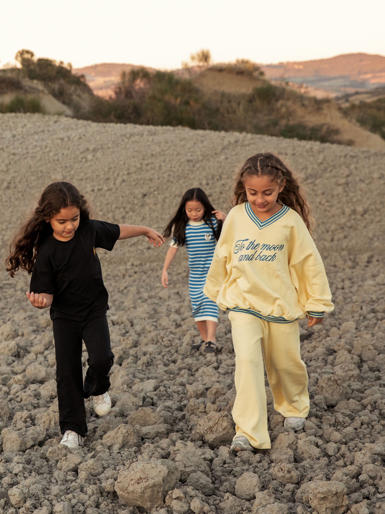 Action shot of children playing while wearing mini rodini To the Moon yellow sweatshirt