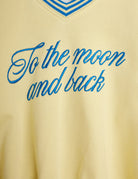 Close-up detail of blue embroidered To the Moon and back script lettering on yellow fabric