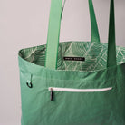Green tote bag with leaf pattern interior and 'Swim Shady' label on a gray background