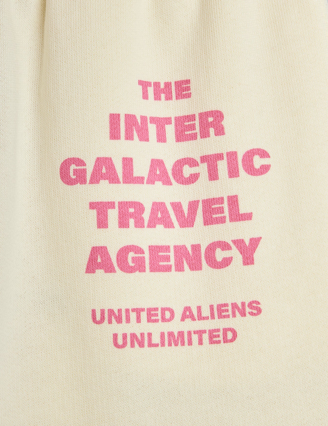 Close-up of Inter Galactic Travel Agency text print in pink lettering on cream fabric