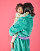 Back view of woman holding child wearing teal Tropicas Adult Cosy Robe with purple waffle texture belt