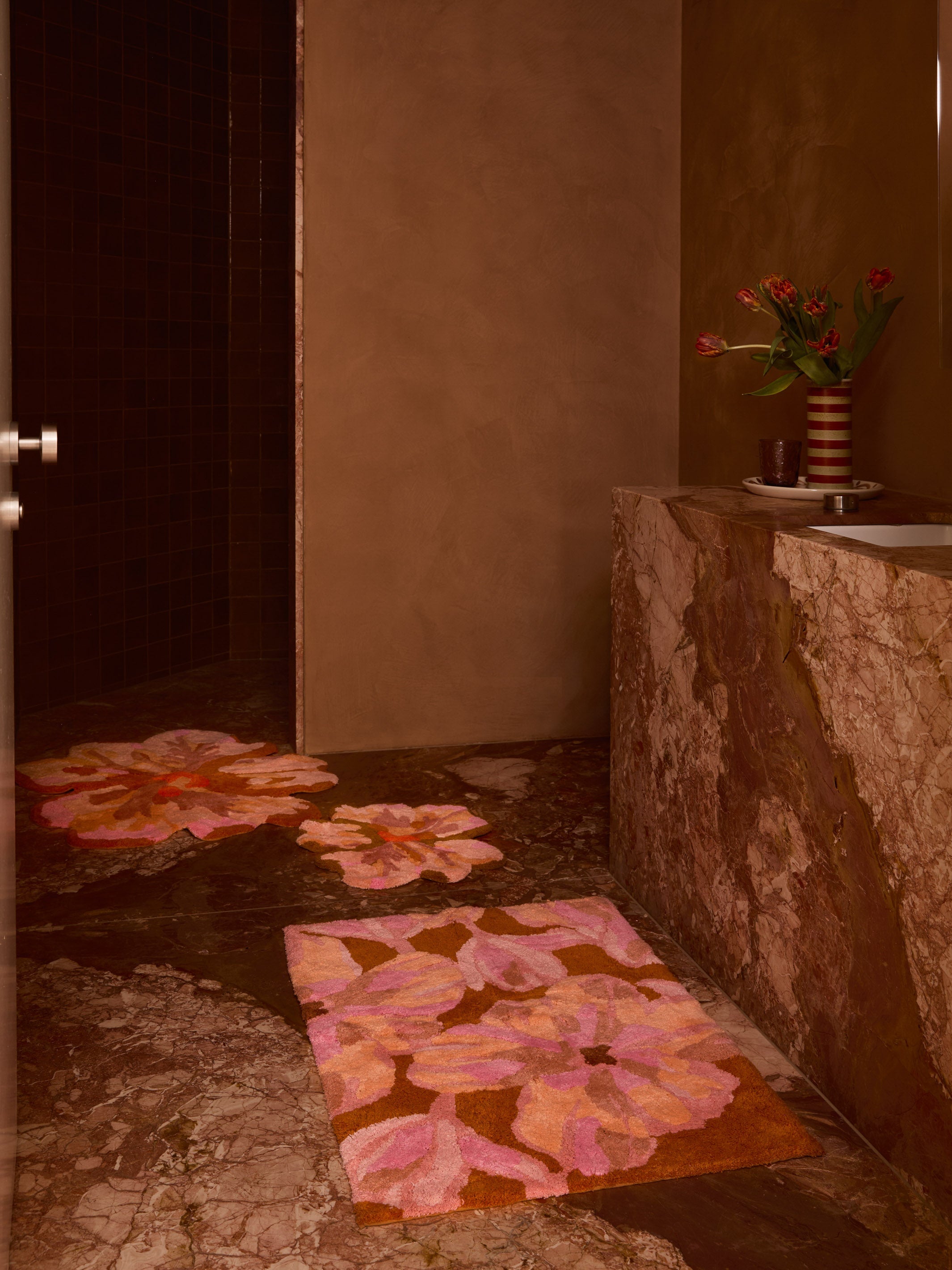 Multiple Tulip Tan Bath Mats arranged in modern bathroom displaying 80cm flower shaped design