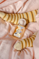 Un Jour Sans Fin fragrance bottle styled with yellow striped socks on pink fabric surface