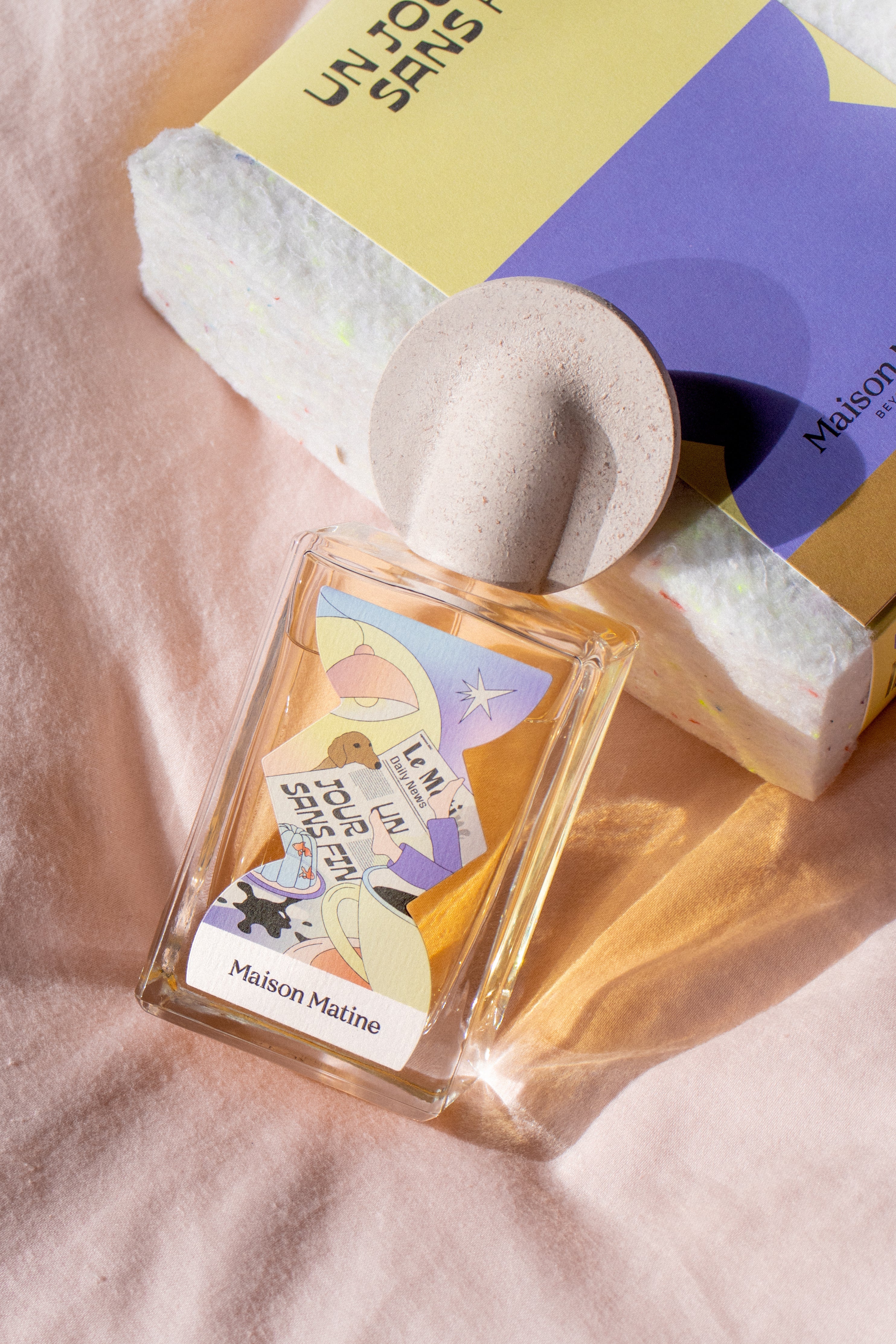 Un Jour Sans Fin perfume with speckled pink cap displayed with packaging box in natural lighting