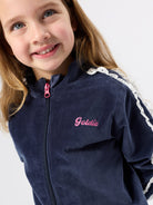 Close-up detail of navy velour sweat jacket showing pink embroidered script logo and white broderie shoulder trim