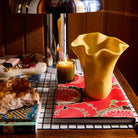 Aspen Gold Violetta Vase with ruffled rim styled on a tiled surface beside a lit candle and books