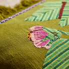 Close-up detail of pink flower applique embroidery on juniper green fabric showing textured stitching