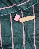 Close-up of green bamboo terry bath sheet with pink stripe pattern and soap styling props