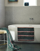 Green striped bamboo terry bath sheet draped over white bathtub in modern bathroom setting