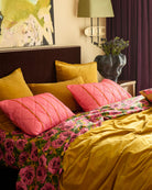 Wategos Soiree Stripe pink quilted pillowcases with orange stripes on bed with yellow velvet cushions