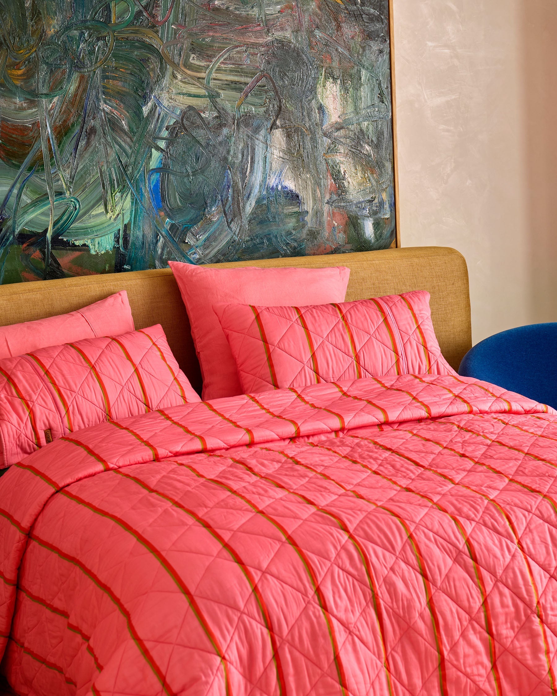 Angled view of pink striped quilted bedding set showing diamond quilting pattern and orange stripe detail