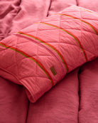 Single Kip Co Wategos Soiree quilted pillowcase on coral sofa showing quilted texture and brand label
