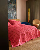 Wategos Soiree Stripe pink quilted bedspread by Kip Co draped over bed in modern bedroom setting