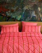 Front view of Wategos Soiree Stripe organic cotton quilted bedspread showing pink color and orange stripe pattern